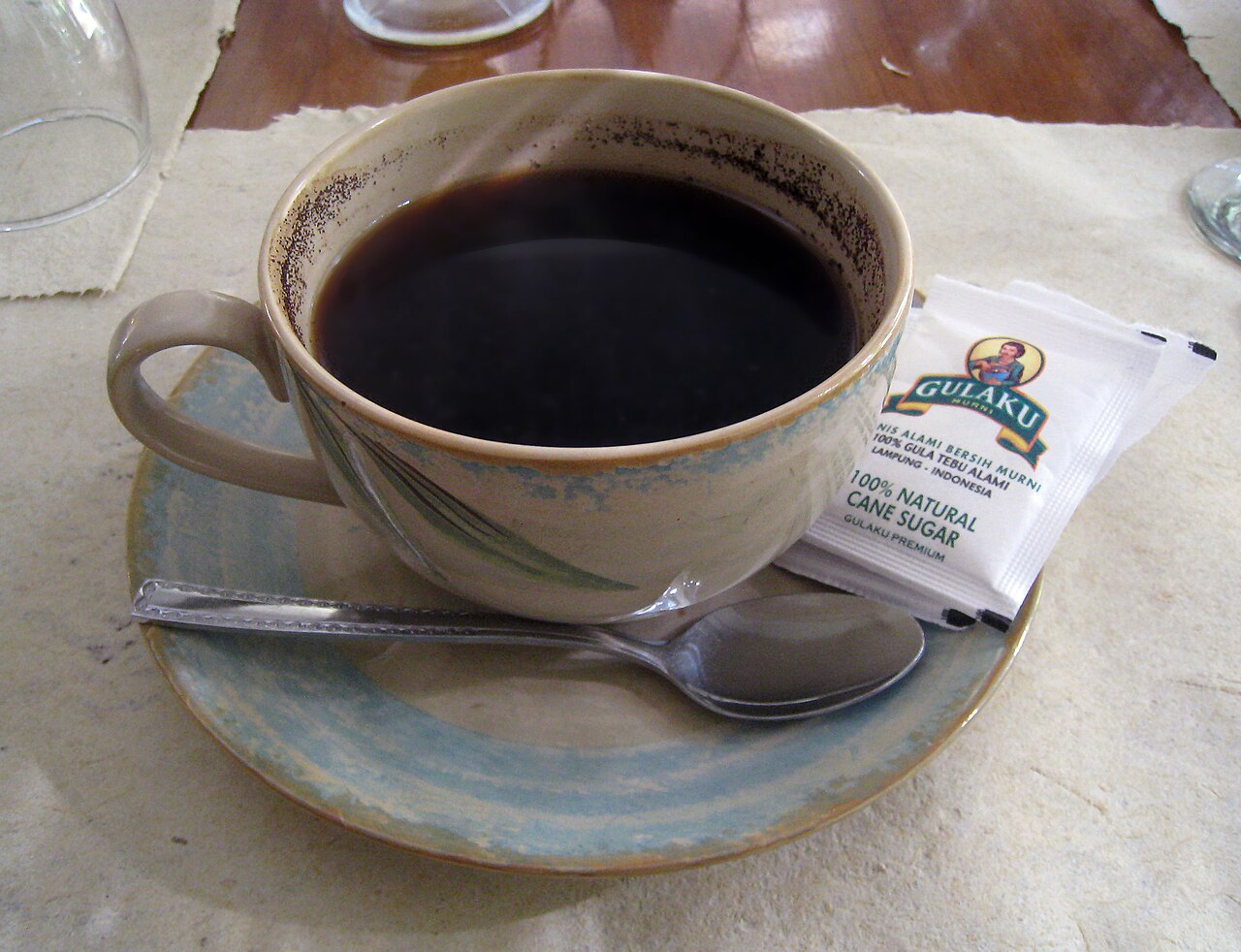 Kopi tubruk dalam cangkir dengan ampas terlihat di tepi bagian dalam.